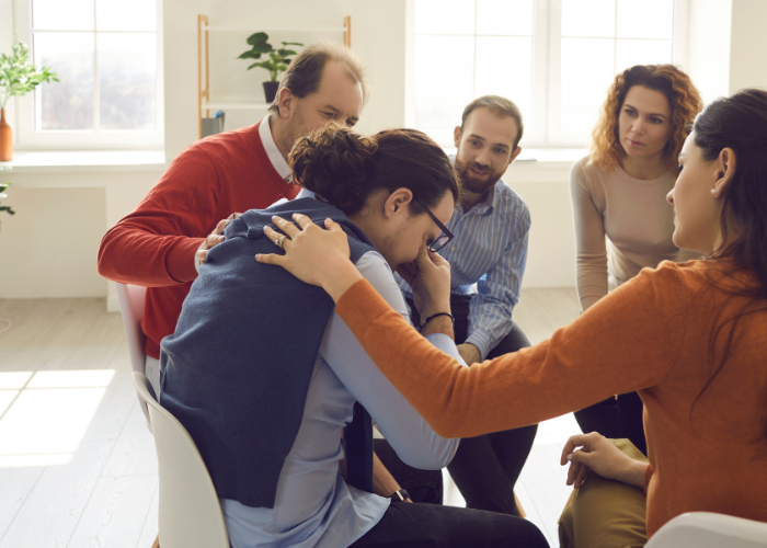 an image of a group of people comforting one of the members
