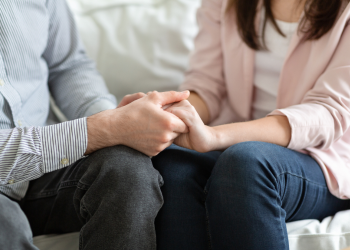 an image of a couple sitting in the couch holding hands together