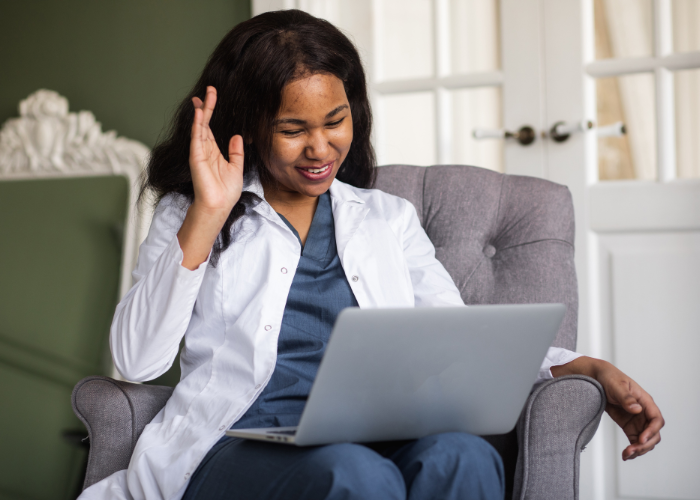 an image of a woman having a call using a laptop waving